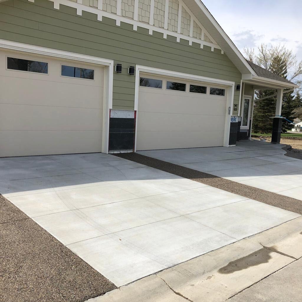 beautiful driveway with two pads and a concrete pebble finish in between and around it